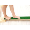 Moje Bambino Grass Balance Board, a child standing on a wooden and green grass-textured balance board for kids' balance and coordination training.
