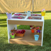 Whitney Brothers outdoorED™ Sensory Table, colorful gardening and watering set up with buckets, flowers, and garden tools outdoors.
