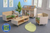 Whitney Brothers elevatED Children's Sofa, a small wooden sofa with green cushioning, in a colorful children's playroom with bookshelves, stuffed animals, and decorative plant.