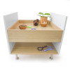 Whitney Brothers elevatED™ Discovery Table, educational children's wooden table with white side panels and two tiered wooden surfaces, featuring toys and a potted plant on the top tier.