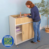 Whitney Brothers elevatED™ Infant Changing Cabinet, a healthcare or childcare facility, featuring a woman tending to a baby inside the cabinet, with storage compartments and a natural wood finish.