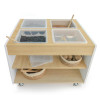 Whitney Brothers elevatED™ Mobile Sensory Table, wooden sensory table with four clear containers filled with different textured materials and sensory tools, on a white mobile stand with baskets for storage.