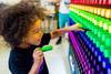 LiteZilla Giant Lite Brite 10' x 6' Light Wall, a young child interacting with colorful illuminated pegs on a large light wall display.