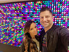 LiteZilla Giant Lite Brite 12' x 6' Light Wall, colorful LED light wall with two people taking a selfie in front of the illuminated display.