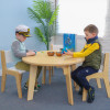 Whitney Brothers Whitney Plus Round Classroom Table - 22H, a light wood round table with two children sitting and playing around it in a bright classroom setting.