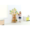 Moje Bambino Classroom Tree Bookshelf, children's room with tree-shaped bookshelf featuring green leaf decorations, young girl playing with toys next to the bookshelf.