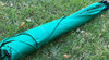 Frame It All Sandbox Tarp Cover - Square, green square tarp cover for sandbox, folded and lying on grass.