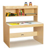 Jonti-Craft Dual Writing Desk, wooden classroom desk with storage shelves on top and paper and writing supplies on the surface.