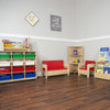 Wood Designs Kids Sofa with Red Cushions, wooden children's sofa with red cushions in a playroom setting.