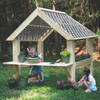 Wood Designs Outdoor Garden Center, children planting flowers in pots on a wooden garden playhouse in a forest setting.