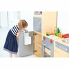Moje Bambino Complete Dramatic Play Kitchen Set #1, a young girl playing with a toy kitchen set with cabinets, a countertop, and pretend food items.