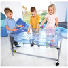 Moje Bambino Mobile Sand and Water Play Table, children playing with water and sand toys on a transparent table.
