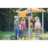 Moje Bambino Outdoor Market Stand, children playing at a wooden outdoor market stall with decorations and fresh produce.