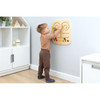 Moje Bambino Touch & Match Sensory Wall Panel, child exploring a wall-mounted wooden sensory panel with colorful movable pieces in a classroom