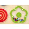 Moje Bambino Spinning Patterns Sensory Wall Panel, green flower-shaped activity panel with colorful spinning beads and part of a red spiral panel on a wooden wall