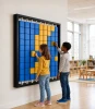 LiteZilla Mosaico Wall with Large Squares STEM Wall Activity, children creating a blue and yellow mosaic pattern with large interactive squares in a classroom.