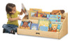 Jonti-Craft Tiny Tots Pick A Book Stand, a wooden children’s bookshelf filled with colorful children's books, with a young girl sitting beside and looking at the books. Jonti-Craft Tiny Tots Pick A Book Stand, a wooden children’s bookshelf filled with colorful children's books, with a young girl sitting beside and looking at the books.