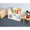Whitney Brothers NewWave Book Display, white wooden book shelf with multiple compartments filled with children's books in a playroom or classroom setting with a Mickey Mouse plush toy sitting on a wooden chair.