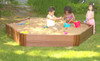 Frame It All Hexagon Wooden Sandbox Kit - 2-inch Profile - 7' x 8' x 11'' with children playing in a sandbox in a garden setting.