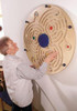 HABA Pro Wall Ball Labyrinth Wall Game, person playing the wooden maze game mounted on wall.