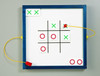 Playscapes Tic Tack Toe Magnetic Wall Game, children’s magnetic tic-tac-toe game on a whiteboard with green X and red O pieces arranged in a game pattern.