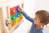 HABA Pro Colorful Squares Sensory Wall Activity, a child exploring and interacting with a wooden sensory wall panel featuring colorful square tiles and knobs for tactile play.