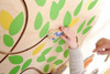 HABA Pro Tree Mirror Interactive Wall Decor, child playing with the wooden tree themed mirror and colorful leaf-shaped accents.