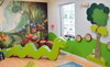 HABA Pro Tree and Animals Meadow Interactive Wall Decor, colorful children's play area with green snake-shaped decor, woodland mural, and large green tree wall piece.