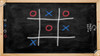 After Mouse Interactive Play Touch Table with Custom Company Logo, black chalkboard surface with tic-tac-toe game drawn in chalk, framed by a light wood border.