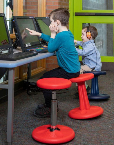Playscapes Active Learning Wobble Stool, 18¾"H, being used by children sitting at computer desks in a classroom or learning center.