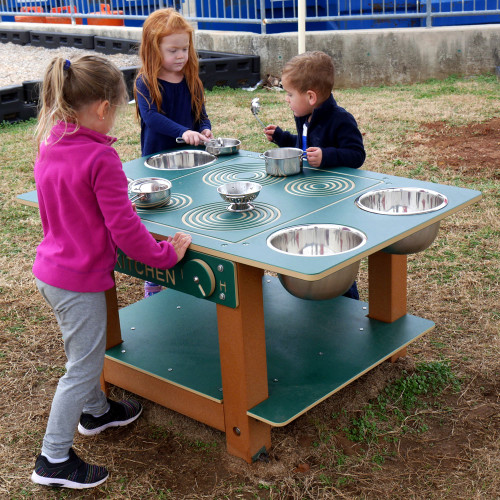Infinity Playgrounds Island Mud Kitchen Commercial Play Table, children playing with toy pots and pans outdoors.