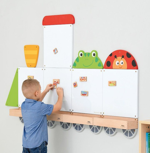 Moje Bambino Toddler Train Magnetic Board Set, a young boy drawing on a white magnetic board with colorful train-themed magnetic pieces.