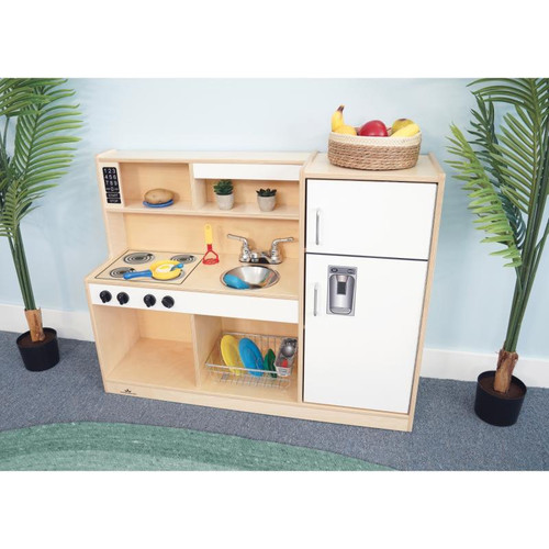 Whitney Brothers Let's Play Toddler Play Kitchen Combo - White, children's wooden play kitchen with stove, sink, countertop, storage shelves, and a basket of play fruits on top.