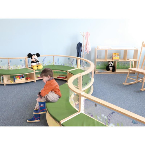 Whitney Brothers Nature View Curve In Couch, children's play area with curved wooden couch featuring green cushions and nature-themed transparent sides, with toys, stuffed animals, and a young boy playing.