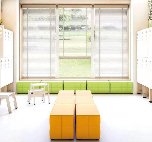 Moje Bambino Upholstered Poufs, colorful padded ottomans and seating cubes in a bright, modern room with large windows and white blinds.