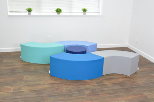 Children's Factory Tranquility Curve Soft Seating - 5 Pieces, colorful modular soft seating for children arranged in a semi-circle on a wooden floor in a bright room.