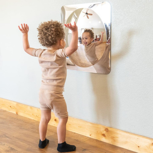 SPARK & WOW Acrylic Bubble Mirror - 1 Large Bubble, a reflection of a happy child playing with the large bubble-shaped acrylic mirror mounted on a wall.