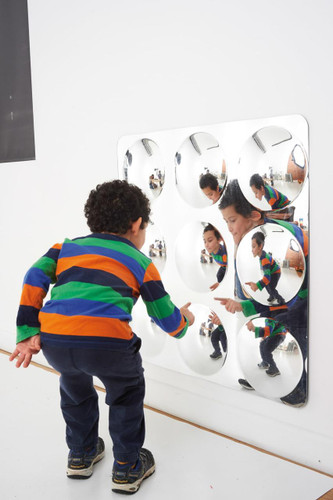 SPARK & WOW Acrylic Bubble Mirror - 9 Giant Bubbles, a child playing with a modern mirror installation featuring nine large reflective bubbles.