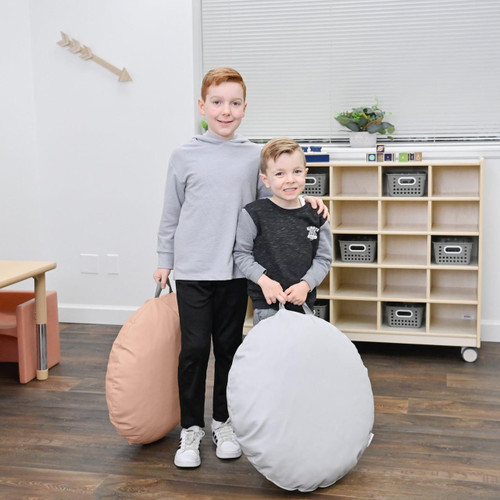 Children's Factory Mini Round Pouf with Handle - Glacier Gray and Clay, kids holding large soft poufs in a classroom setting.