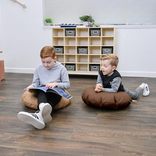 Children's Factory Mini Round Pouf with Handle - Walnut and Almond, two children sitting on brown and tan poufs in a classroom or playroom environment.