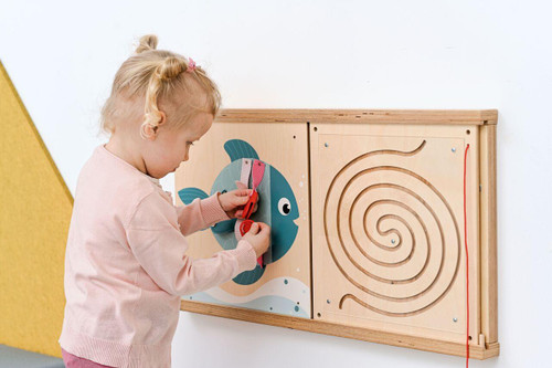 Moje Bambino Fish Fine Motor Skills Wall Panel, a children's educational wooden wall attachment with a fish-shaped maze game and a string for improving fine motor skills.