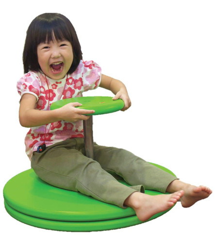 The Freckled Frog Whizzy Dizzy Sit 'n Spin, a colorful green spinning toy for children, with a happy girl sitting on it and holding the central pole, smiling joyfully.