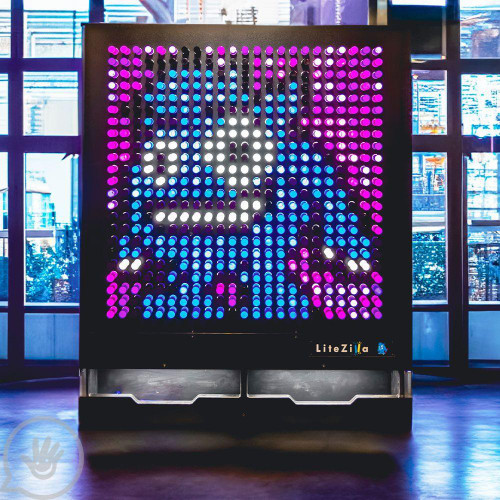 LiteZilla Giant Lite Brite - 4' x 5' LED light-up art display featuring a colorful pixelated image of Sonic the Hedgehog, illuminated in vibrant pink, purple, blue, and white lights, located in a modern indoor setting.