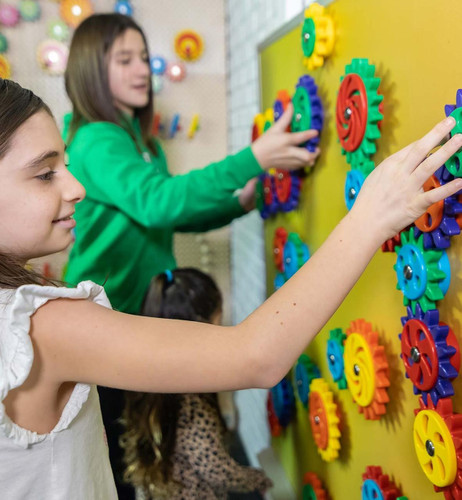 LiteZilla MagWiz Magnetic Wall Gears, children playing with colorful magnetic gears on a yellow wall for educational fun and STEM learning.