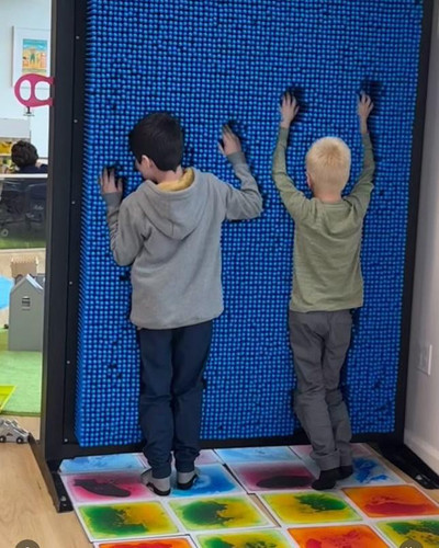LiteZilla Clone Box Giant Pin Wall STEM Activity, two children playing on a large interactive foam wall with colorful floor tiles.