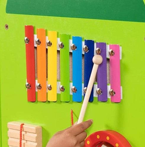 SPARK & WOW Xylophone Hammer Wand for Crocodile Wall Toy, colorful wooden xylophone with metal bars in red, orange, yellow, green, blue, purple, and pink on a green wall.