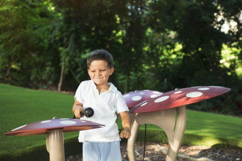 Freenotes Musical Mushrooms, children's outdoor musical instrument resembling mushroom-shaped chimes played with mallets, in a park setting.