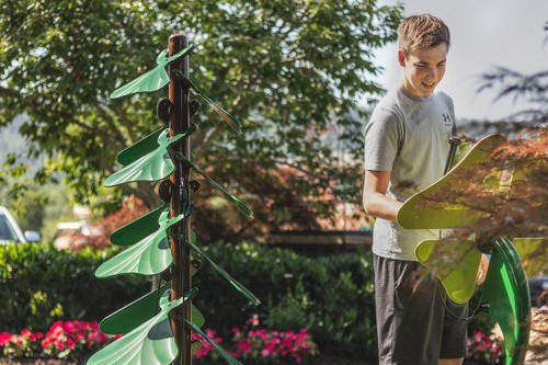 Freenotes Garden Bed Ensemble Musical Playground Set, outdoor musical play equipment with multiple green wind chimes and a young boy playing a green xylophone in a garden setting.
