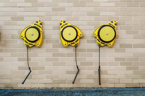 Freenotes Honeycomb Harmony Ensemble, yellow musical percussion instruments mounted on a wall with sticks for playing.