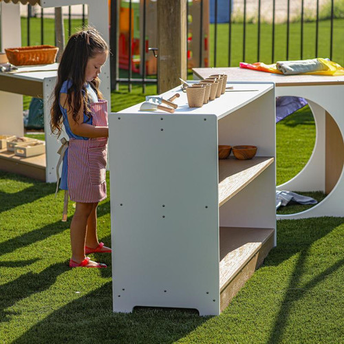 Whitney Brothers outdoorED™ Storage Shelf, a white outdoor storage furniture unit with multiple shelves and compartments, placed outside on a grassy area for children to store toys and outdoor play items.